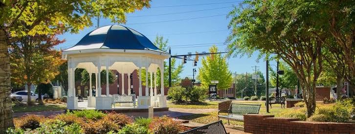 Town park gazebo with benches and leafy trees in Canton, Georgia.