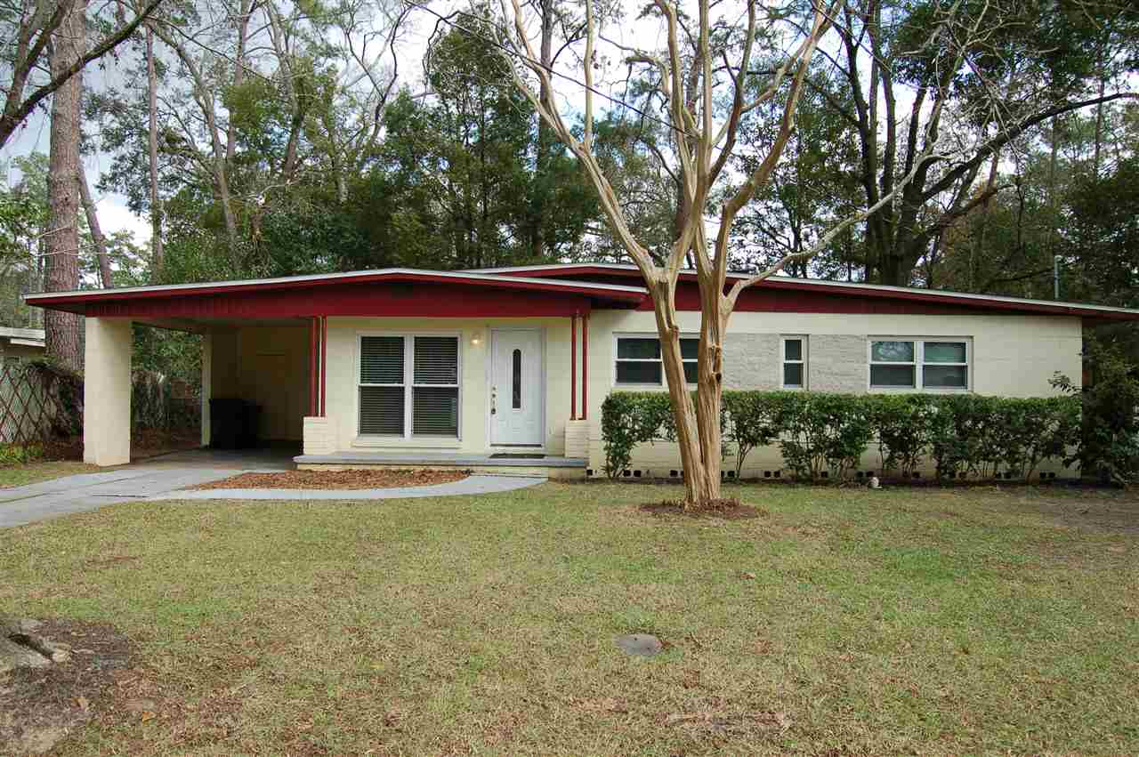 A charming home featuring a red roof surrounded by lush green grass.