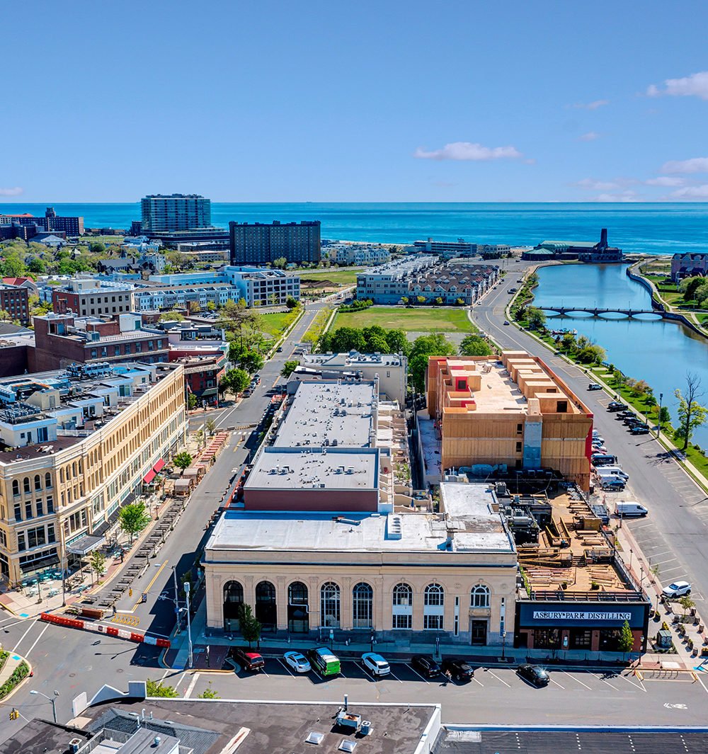 Aerial view of 574 Cookman Avenue under construction, with Asbury Park streets, waterways, and ocean beyond.