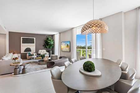Open-plan dining and living room with a round table and floor-to-ceiling windows.