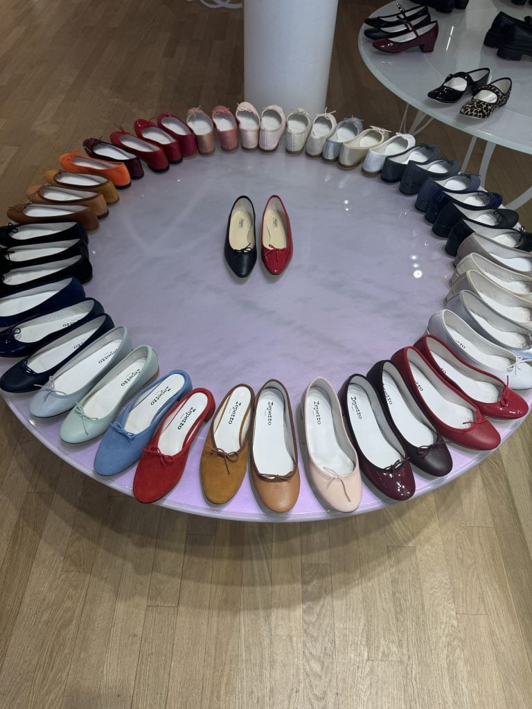 Colorful ballet flats arranged in a circle around two centered shoes on a round display table.