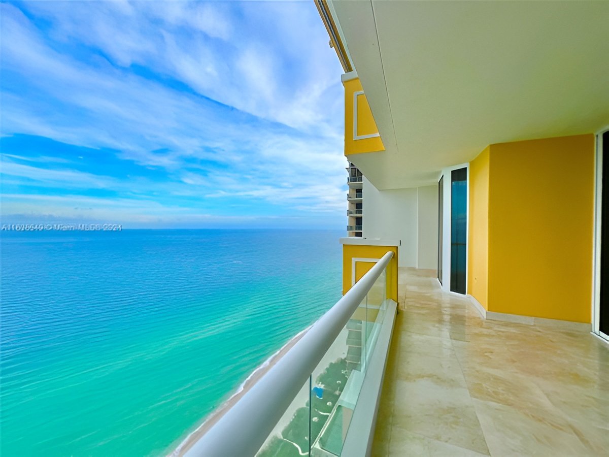 Oceanfront balcony with a glass railing and expansive turquoise sea view.