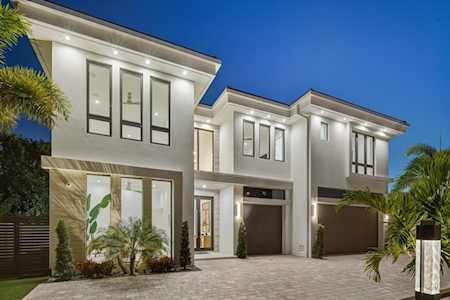 Modern two-story white home with large windows and stone accents, illuminated at night.
