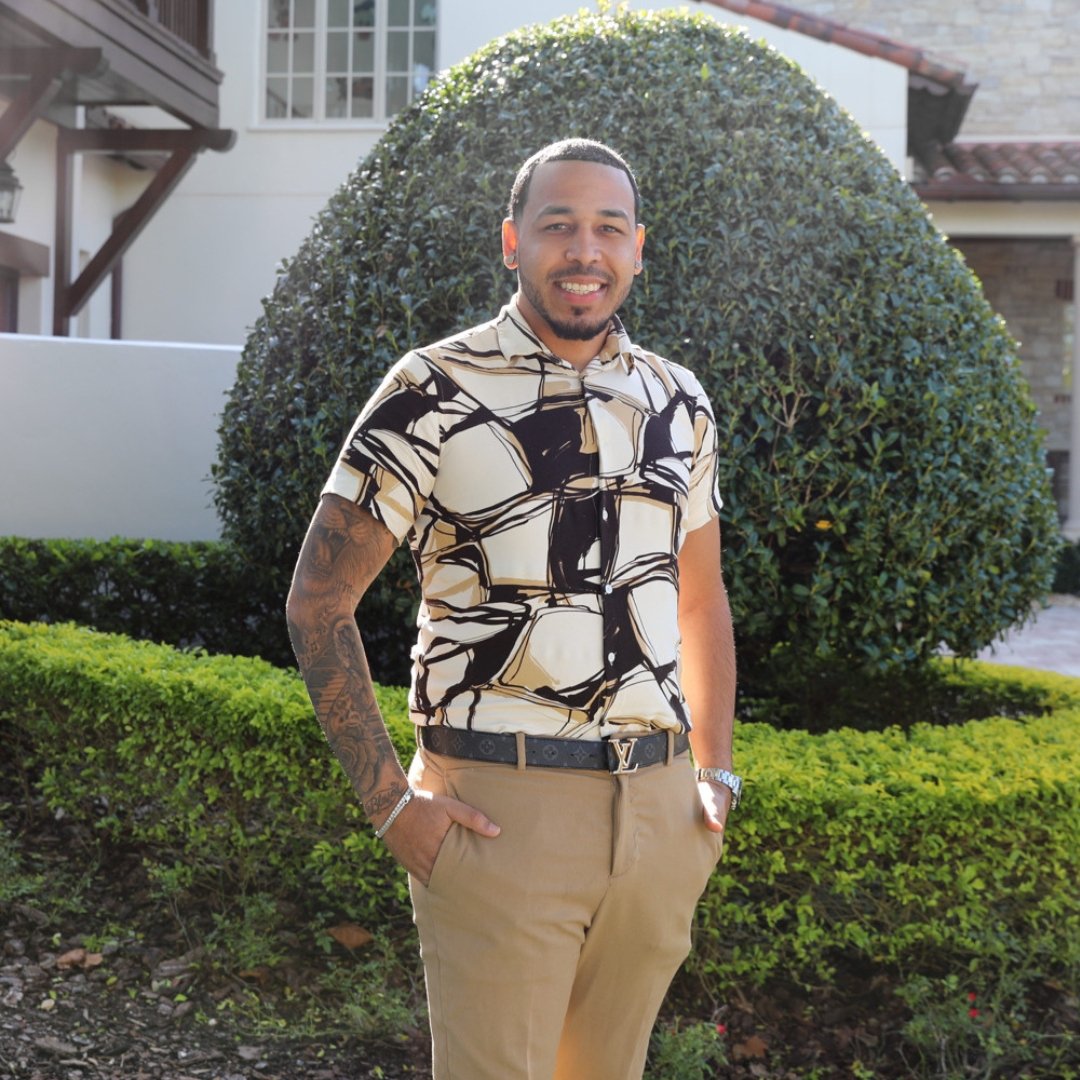 Yeudis Alcantara standing in front of a large rounded hedge.