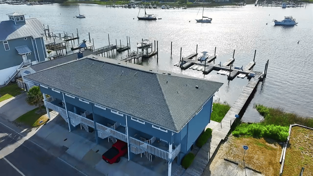 Aerial view of a blue waterfront building with private docks and boats along the canal.