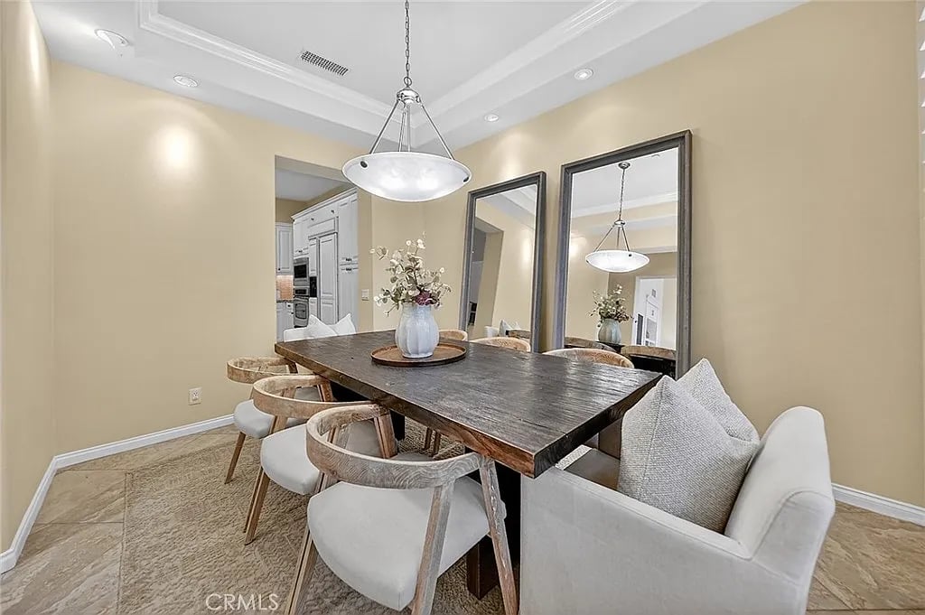 Dining room with a dark wood table, upholstered chairs, and large wall mirrors.