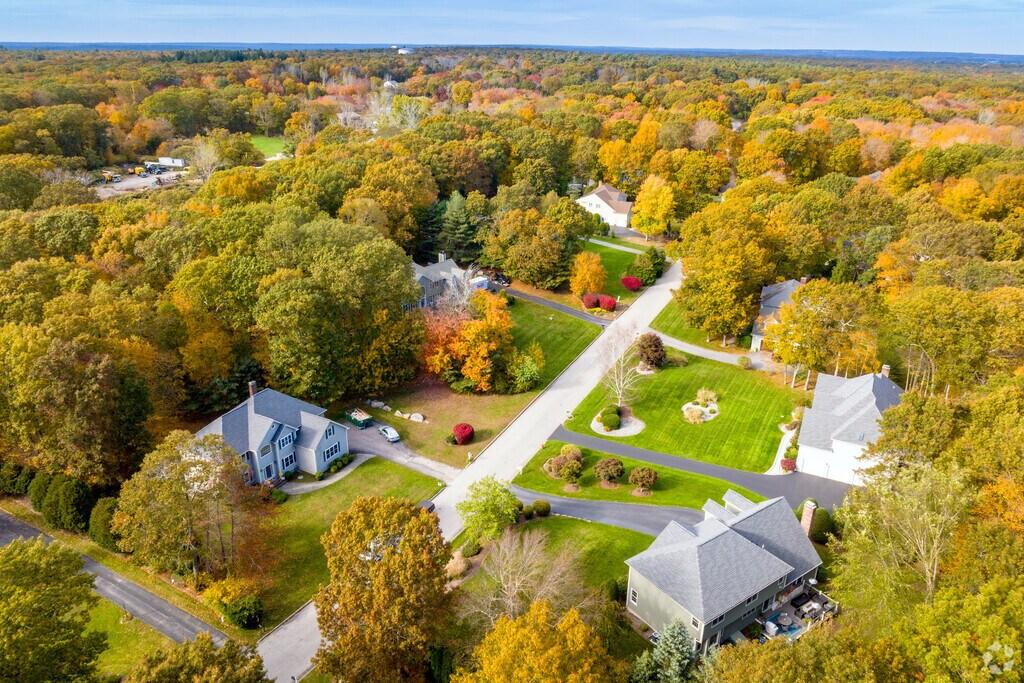 Aerial view of homes along winding streets amid colorful autumn trees.