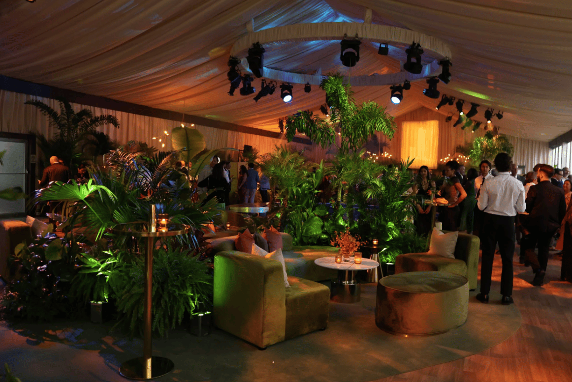 Reception event in a tented space with tropical plants and lounge seating.