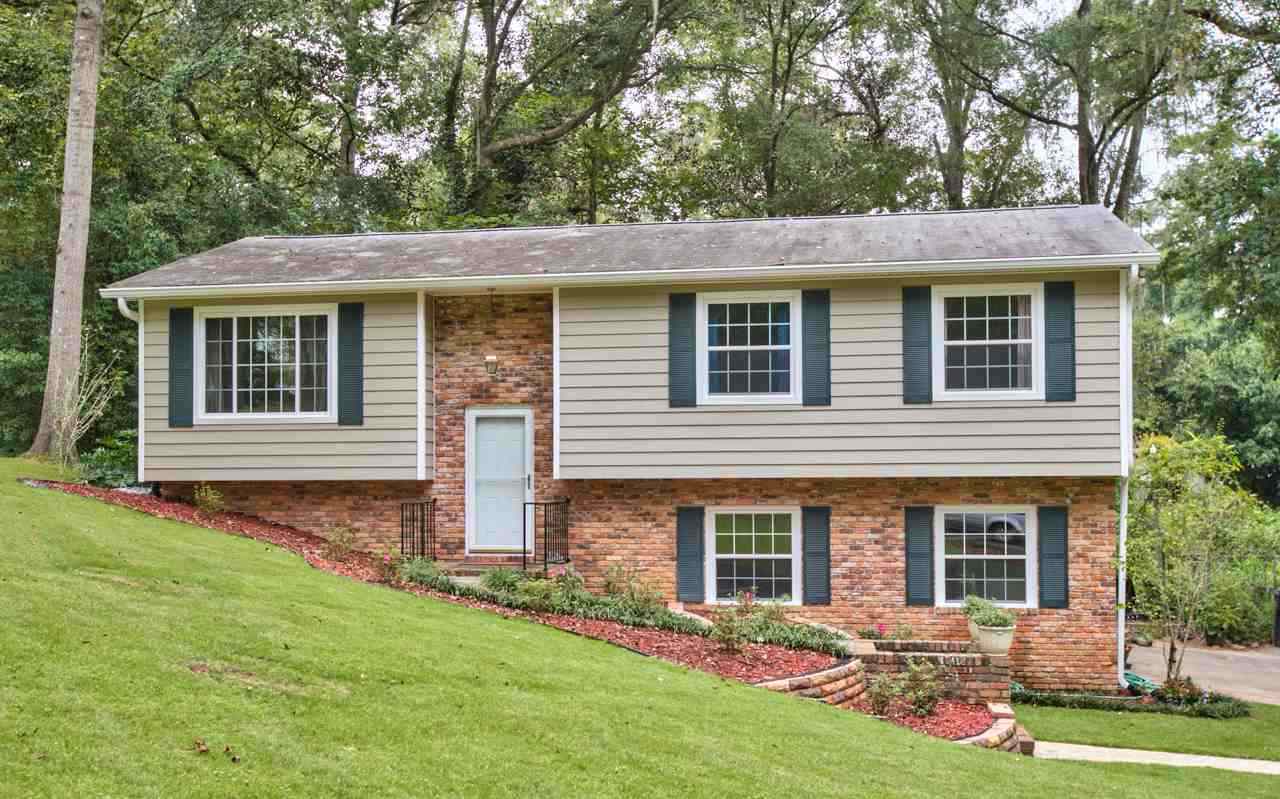 A brick home surrounded by lush green grass and trees, creating a serene and inviting outdoor environment.