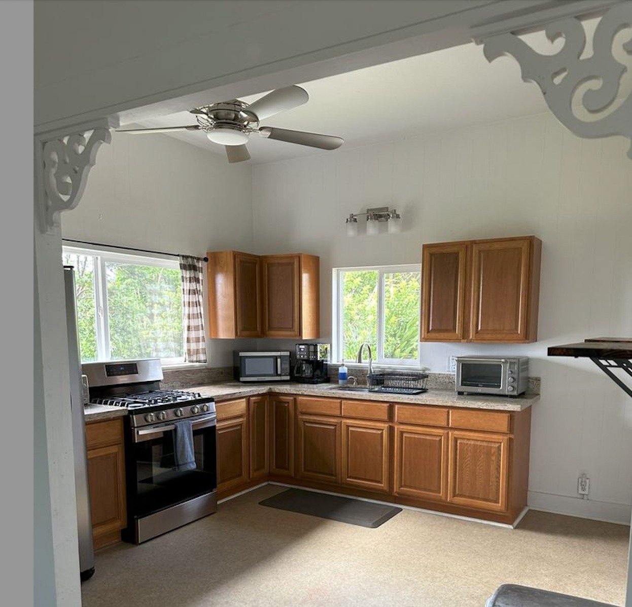Kitchen with warm wood cabinets, a stainless steel range, and large windows overlooking greenery.