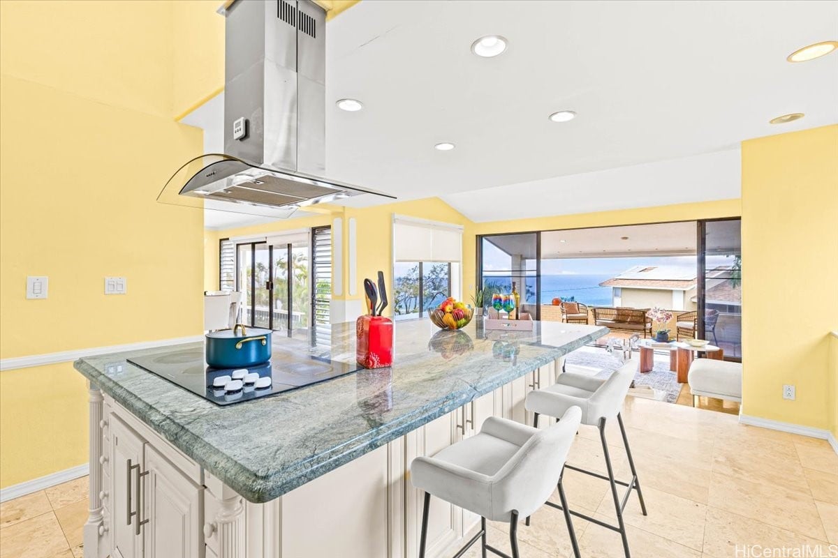 Kitchen with a green stone island and ocean views through sliding glass doors.