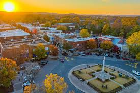Aerial view of downtown buildings and a circular plaza with a central monument at sunset.