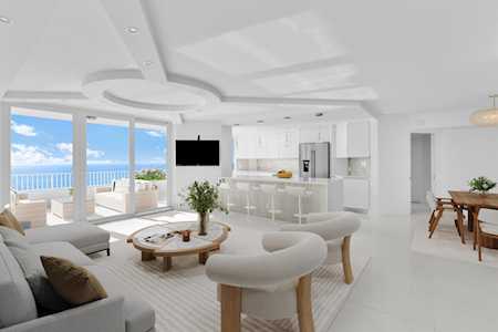 Open-plan living room with curved seating and an ocean view through sliding glass doors.