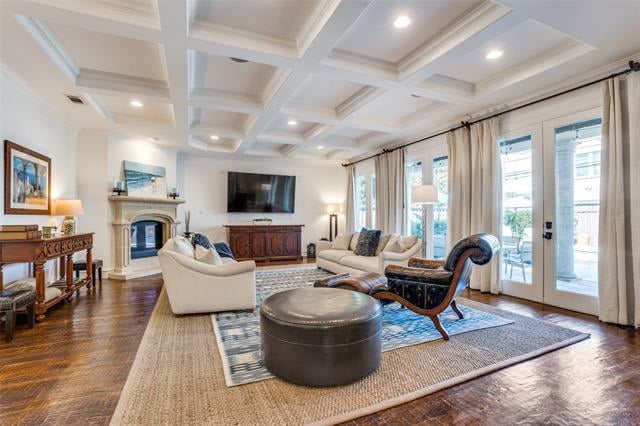 Living room with a coffered ceiling, fireplace, hardwood floors, and French doors to a patio.