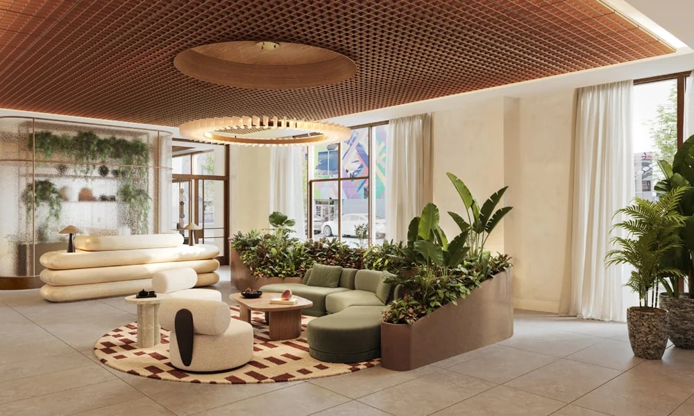 Lobby lounge with a green sectional, tropical plants, and a wood lattice ceiling.