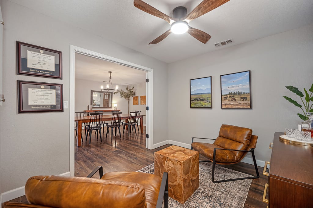 Living room with leather seating and a wood coffee table, opening to a dining room.