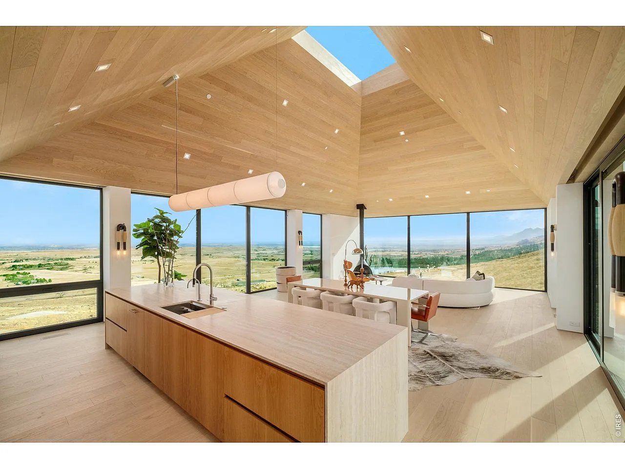 Open-plan kitchen and living area with a wood island, skylight, and wide mountain and plains views.