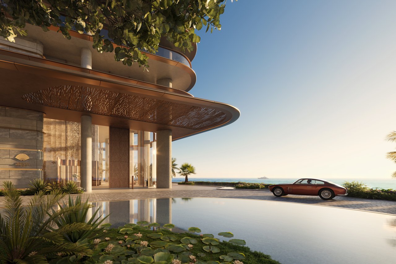 Waterfront building entrance with a sweeping curved canopy, reflecting pool, and vintage car.