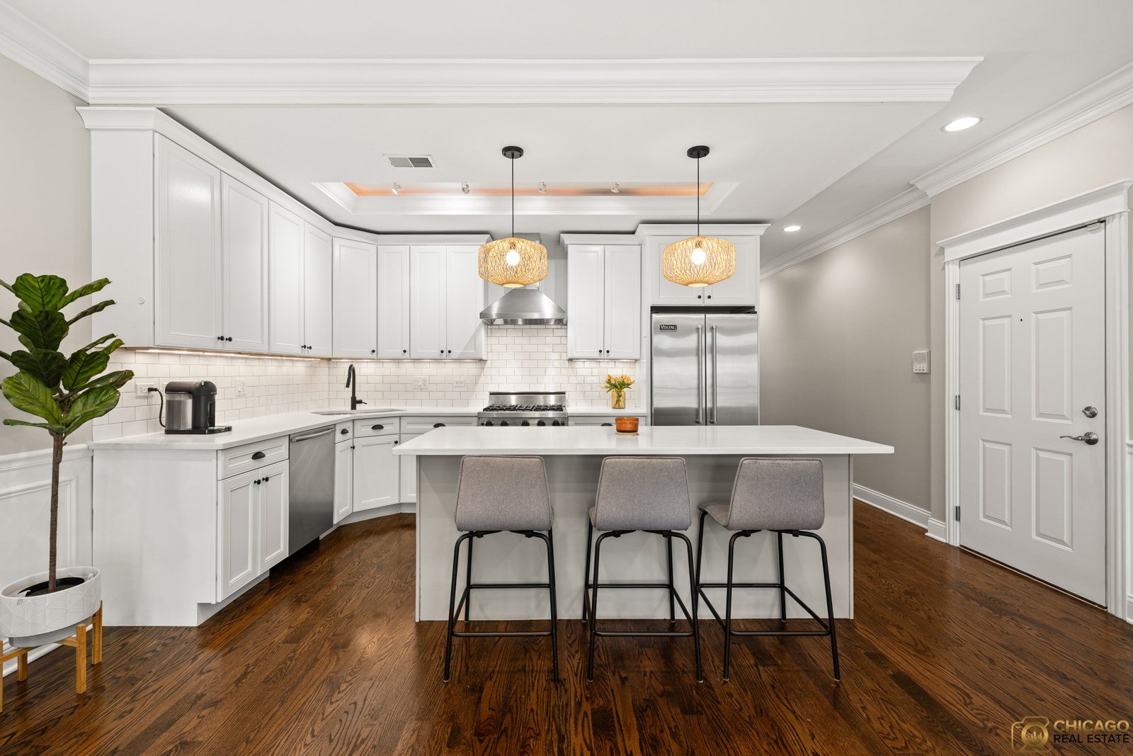 White kitchen with a large island and rattan pendant lights at 3822 N. Damen Ave., a North Center condo listed by Dee Savic