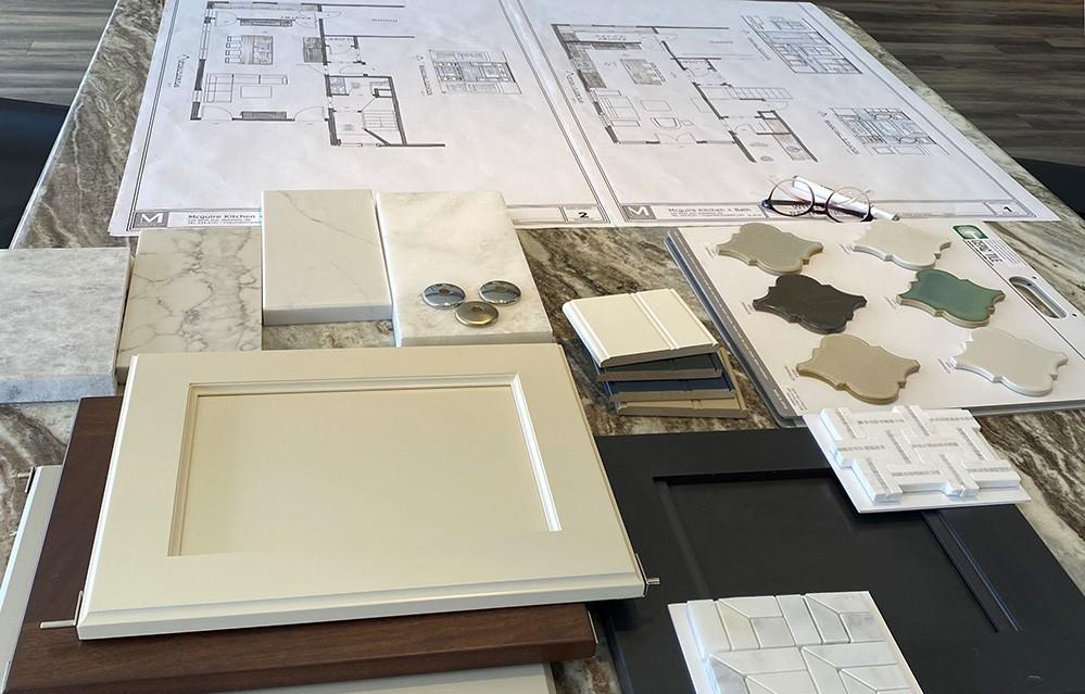 Home floor plans and cabinet, countertop, and tile samples arranged on a stone surface.