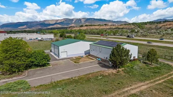 Aerial view of two commercial buildings with mountains in the background.