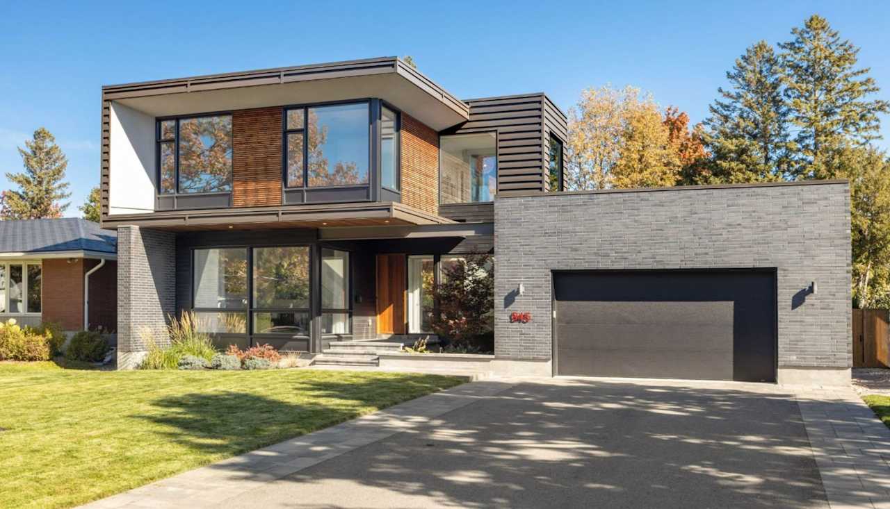 Modern two-story home with wood siding, a gray brick facade, and an attached garage.