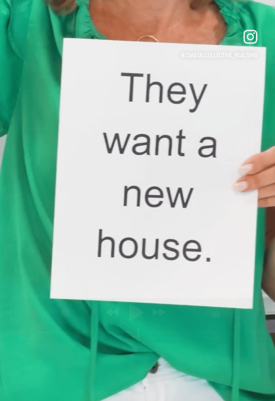 A person in green holds a sign reading “They want a new house.”