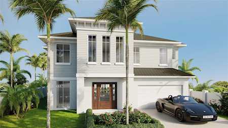 Modern white two-story home with a central entry, attached garage, and palm trees.