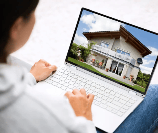 Person viewing a modern two-story house on a laptop.