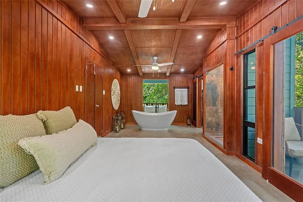 Wood-paneled bedroom with freestanding bathtub