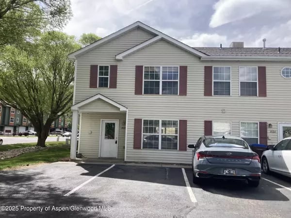 Two-story residential building with maroon shutters and cars parked outside.