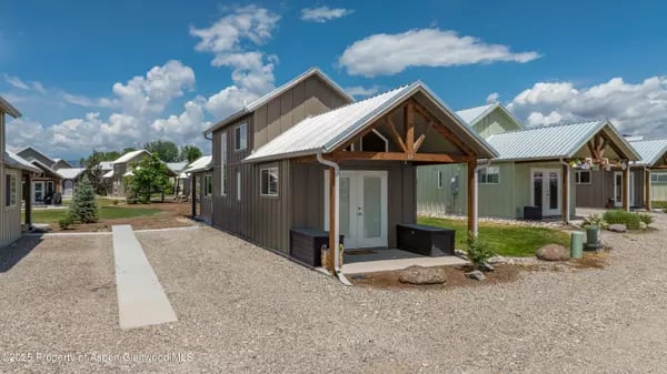 Small modern homes with metal roofs and covered porches along a gravel walkway.