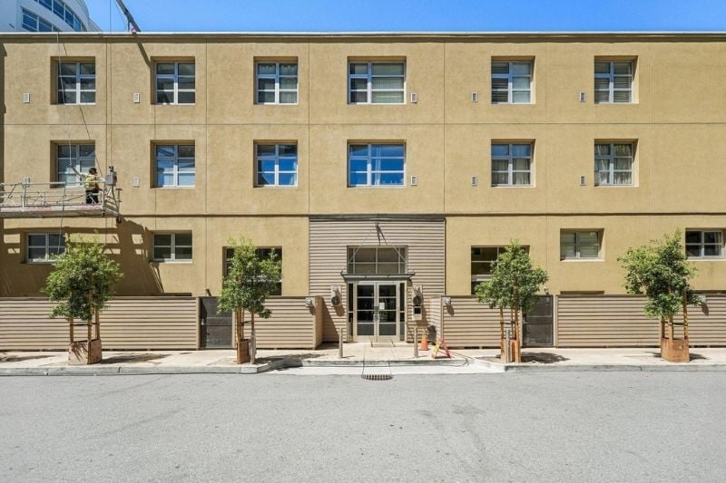 Street-level view of the Harbor Lofts building, highlighting the main entrance and the symmetrical arrangement of windows and trees.