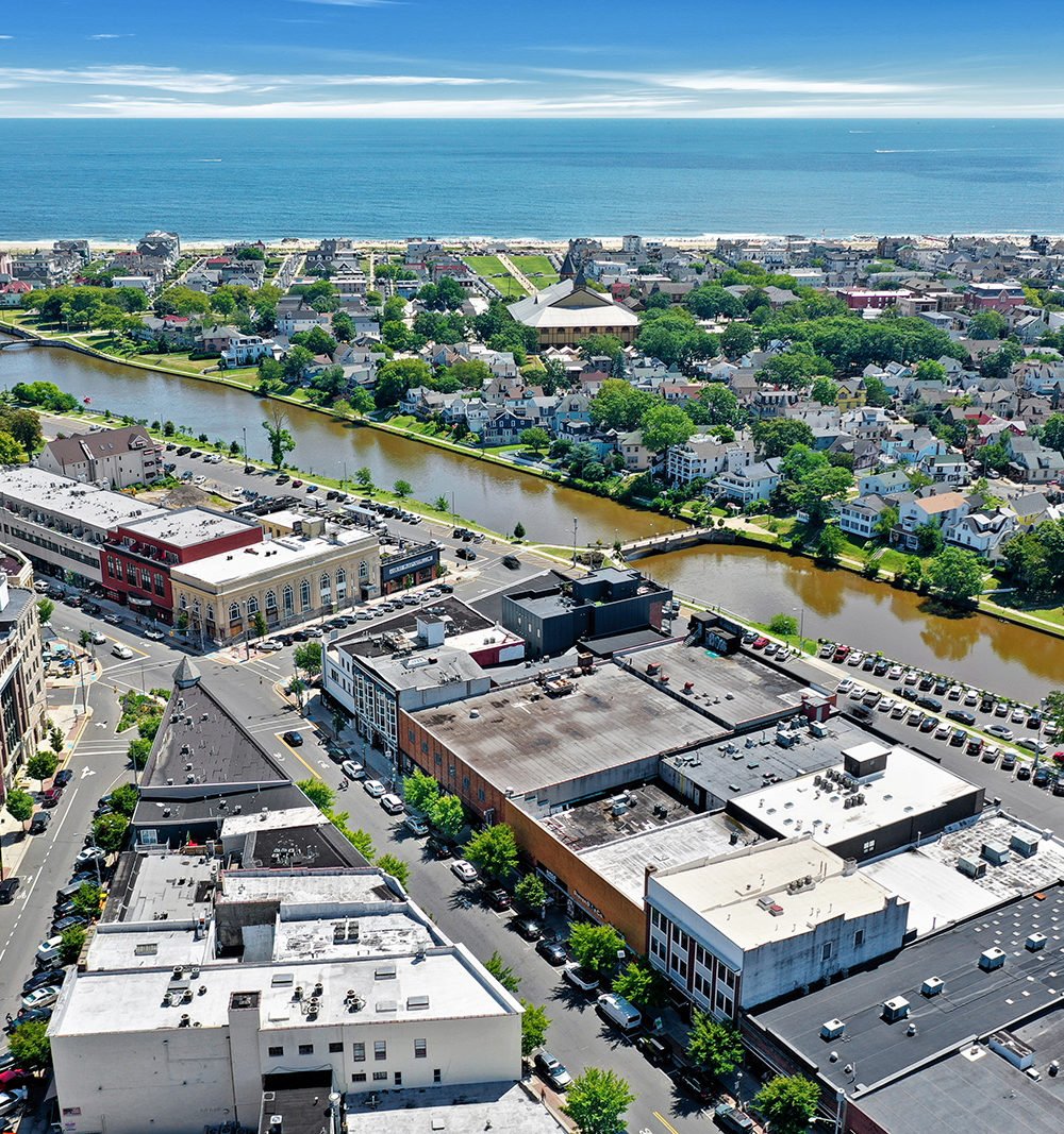 Aerial view of downtown rooftops, a winding river, and the ocean beyond.