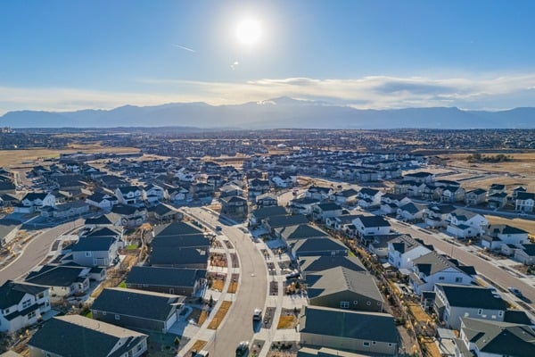Aerial view of Colorado Springs homes and curving streets, with mountains on the horizon.