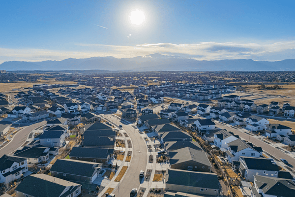 Aerial view of a residential subdivision with curving streets and distant mountains.