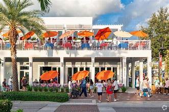 Two-story restaurant with orange umbrellas over its outdoor patio dining area.