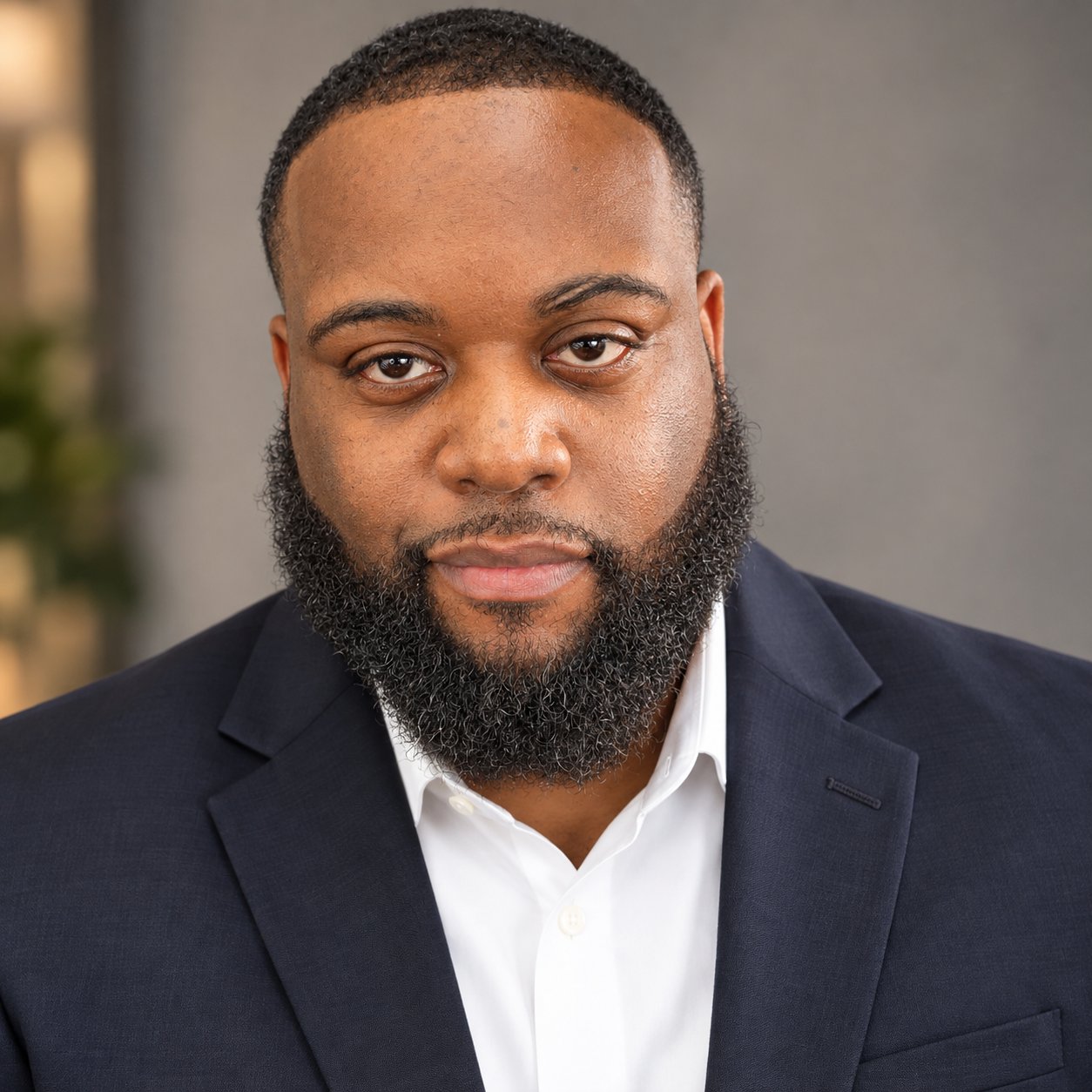 Sedrick Mosley in a navy suit and white shirt, with a full beard.