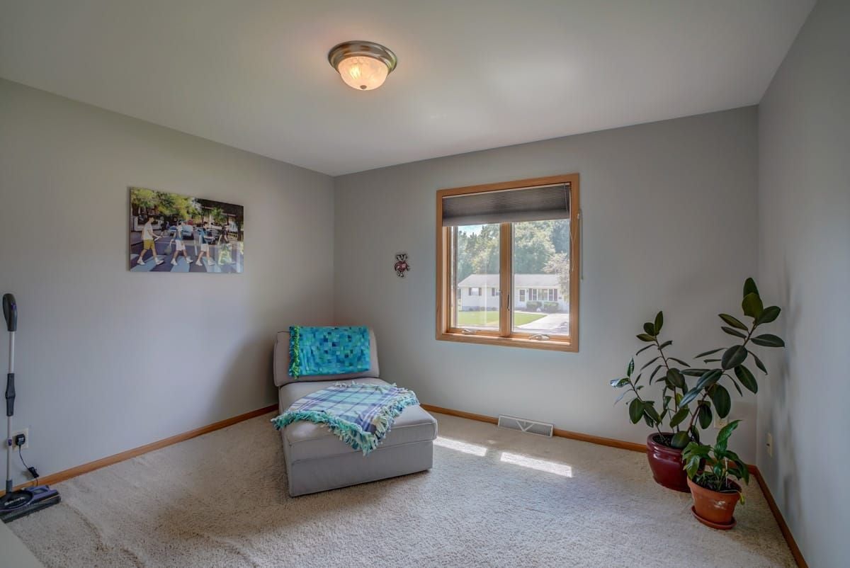 Furnished sitting room with a blue-draped chair, potted plants, and a sunny window.
