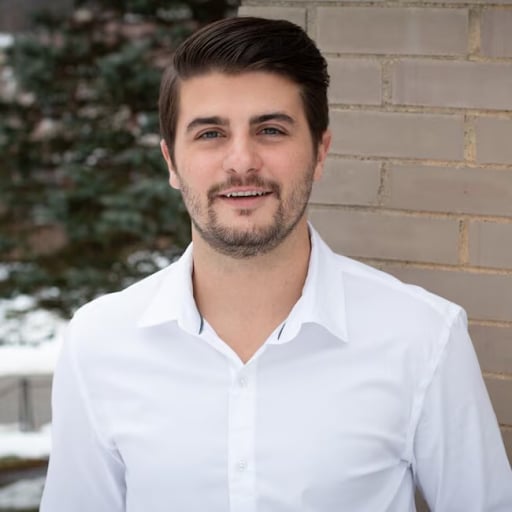 Dylan Marshall, wearing a white shirt in front of a brick wall.