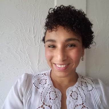 Ebony Lopez smiling in a white lace-trimmed blouse.