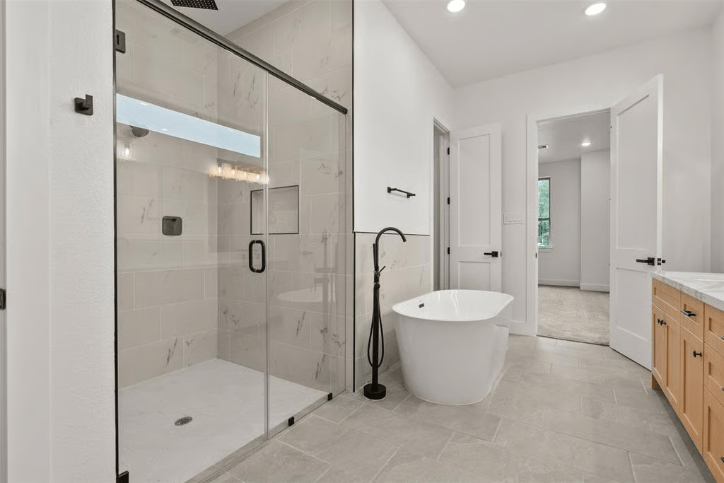 Modern bathroom with a glass walk-in shower, freestanding soaking tub, and light wood vanity.