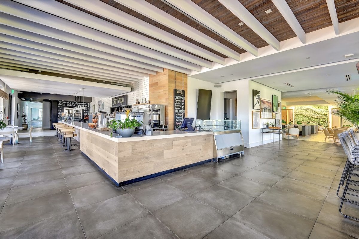 Inside the Driftwood Cafe at The Club at Kalea Bay, with the coffee counter, pastry case and chalkboard menus.
