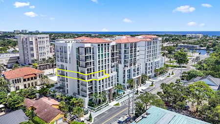 Aerial view of modern condominium buildings, with one section outlined in yellow and water in the distance.