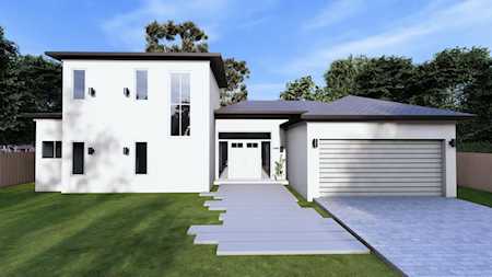 Modern white two-story home with a flat roof, two-car garage, and paved walkway.