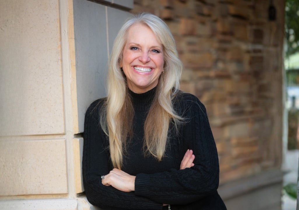 Sharla Jolley Ellis smiling with arms folded against a brick-and-stone wall, representing confidence, calm, and the power of preparation.