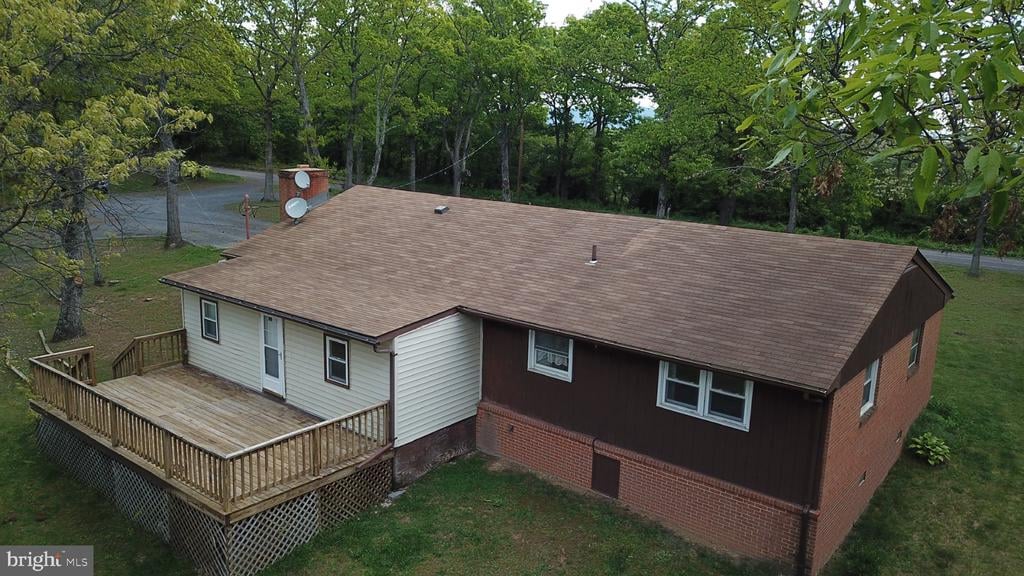 Aerial view of a single-story home with a large wooden deck and mature trees.
