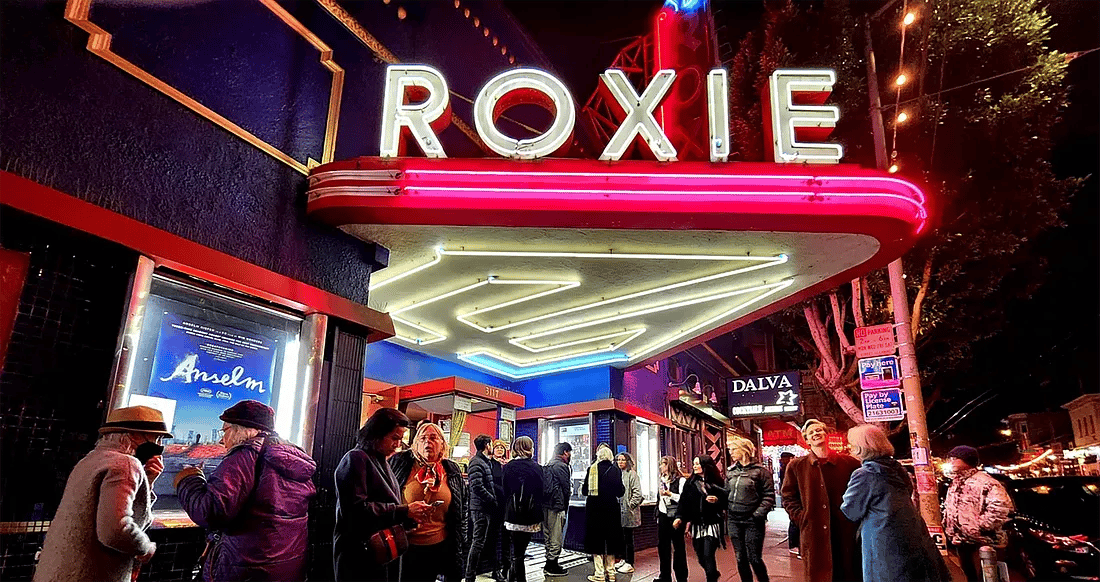 Cinema Glow: The Roxie Theater lights up the night in San Francisco with its vibrant neon sign, drawing a crowd eager for a movie night, including a screening of Anselm. Photo by Saul Sugarman for The Bold Italic.