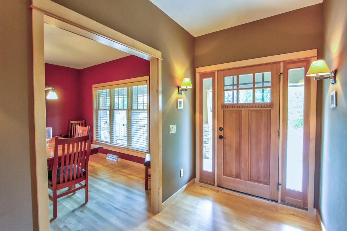 Home entryway with a wood front door and an open view into a red-walled dining room.
