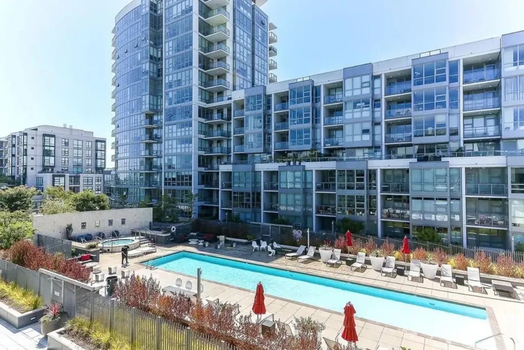 Rooftop swimming pool and lounge area at the Madrone, surrounded by lush landscaping and lounge chairs with red umbrellas.